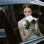 bride-with-black-car-near-glass-skyscraper