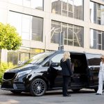 female-chauffeur-waits-business-people-near-minivan-taxi