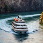 scenic-cruise-ship-sailing-through-rocky-canyon-with-turquoise-water-lush-cliffs