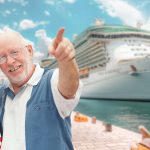 senior-adult-couple-enjoying-view-from-dock-with-passenger-cruise-ship-background